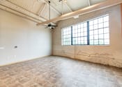 Thumbnail 9 of 16 - A large empty room with a ceiling fan and a window.
