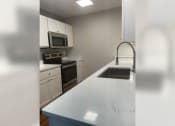 Thumbnail 26 of 35 - a kitchen with white cabinets and a white counter top