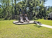 Thumbnail 4 of 11 - A playground with a slide and a bench in the foreground.