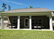 Thumbnail 3 of 11 - A house with a covered patio and a white door.