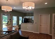 Thumbnail 8 of 11 - A brown leather couch sits in a living room with a dining table and chairs.