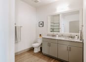 Thumbnail 7 of 22 - A bathroom with a toilet, sink, and mirror.