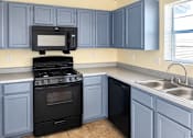 Thumbnail 4 of 6 - A kitchen with a black stove and blue cabinets.