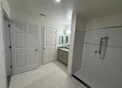Thumbnail 2 of 9 - A white bathroom with a shower, sink, and two doors.