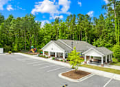 Thumbnail 5 of 6 - A parking lot with a building and a tree in the middle.