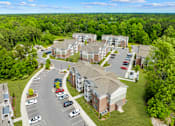 Thumbnail 4 of 6 - A large apartment complex with a parking lot in front.