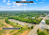 Thumbnail 2 of 7 - A bird's eye view of a residential area with a water tower and a road leading to a town.