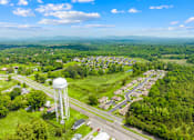 Thumbnail 3 of 7 - A water tower stands in a green field next to a road.