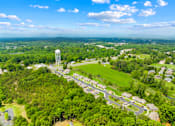Thumbnail 5 of 7 - A water tower stands in a green field with houses in the background.