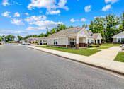 Thumbnail 1 of 7 - A street view of a residential area with houses on the right and a clear blue sky above.