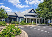 Thumbnail 3 of 23 - A blue building with a grey roof and a parking lot in front.