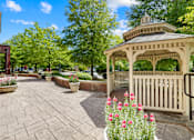 Thumbnail 4 of 13 - A gazebo is surrounded by a brick patio and a black railing.