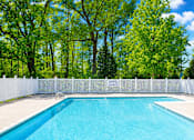 Thumbnail 7 of 19 - A swimming pool surrounded by a white fence and trees.