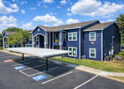 Thumbnail 4 of 23 - A parking lot with a blue building and a covered parking area.