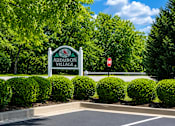 Thumbnail 8 of 19 - A sign for Audubon Village stands in front of a row of bushes.