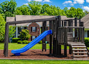 Thumbnail 6 of 19 - A playground with a blue slide and a wooden structure.