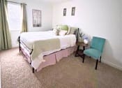 Thumbnail 8 of 17 - A bedroom with a bed, chair, and pictures on the wall.