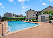 Thumbnail 3 of 31 - A pool surrounded by chairs and a fence with a building in the background.