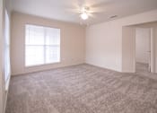 Thumbnail 22 of 33 - an empty living room with carpet and a ceiling fan