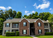 Thumbnail 5 of 19 - A two-story brick apartment building with a balcony on the second floor.
