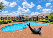 Thumbnail 25 of 27 - A pool with a seal statue in front of apartment buildings.