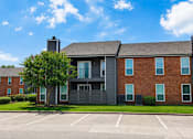 Thumbnail 20 of 27 - A modern brick building with a large parking lot in front.