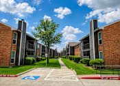 Thumbnail 19 of 27 - A row of apartment buildings with a blue handicap parking sign in the foreground.
