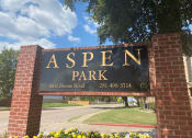 Thumbnail 5 of 26 - a sign for aspen park in front of a brick sign
