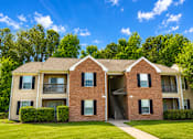 Thumbnail 3 of 19 - A two-story brick apartment building with a green lawn in front.
