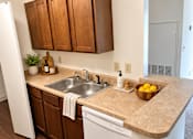 Thumbnail 19 of 50 - A kitchen with a sink, a bowl of lemons, and wooden cabinets.