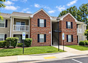 Thumbnail 6 of 50 - A red brick apartment building with a parking sign in front.