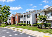 Thumbnail 7 of 50 - A row of townhouses with a parking lot in front.