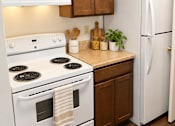 Thumbnail 20 of 50 - A white stove and oven with a white refrigerator in a kitchen.