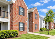 Thumbnail 2 of 50 - A red brick building with a white porch and black shutters.