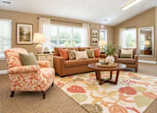 Thumbnail 13 of 50 - A living room with a floral patterned rug and a brown couch.