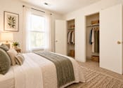 Thumbnail 27 of 50 - A bedroom with a large bed and a closet with clothes hanging.