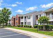 Thumbnail 49 of 50 - A row of apartment buildings with a parking lot in front.