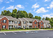 Thumbnail 5 of 50 - Apartment complex with a parking lot in front.