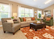 Thumbnail 12 of 50 - A living room with a patterned chair and a couch with throw pillows.
