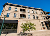 Thumbnail 2 of 7 - A large building with a black awning and a tree in front of it.