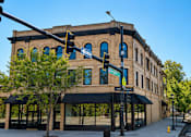 Thumbnail 5 of 7 - A street view of a building with a blue sign on it.