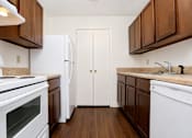 Thumbnail 12 of 19 - A kitchen with white appliances and brown cabinets.
