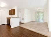 Thumbnail 13 of 19 - A spacious living room with a kitchen area in the background.