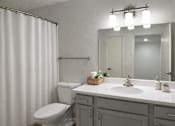 Thumbnail 12 of 18 - A white toilet sits next to a sink in a bathroom.