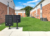 Thumbnail 16 of 25 - A black panel with white numbers stands in front of a brick building.