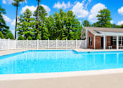 Thumbnail 3 of 19 - A pool in front of a house with trees in the background.