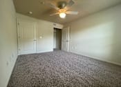 Thumbnail 12 of 15 - A room with a ceiling fan and carpeted floor.
