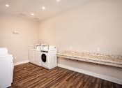 Thumbnail 10 of 13 - A white dryer and washing machine in a room with wood flooring.