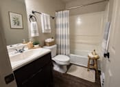 Thumbnail 5 of 14 - A bathroom with a toilet, sink, and shower.