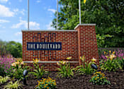 Thumbnail 2 of 14 - The Boulevard sign is mounted on a brick wall with three flags flying in the background.